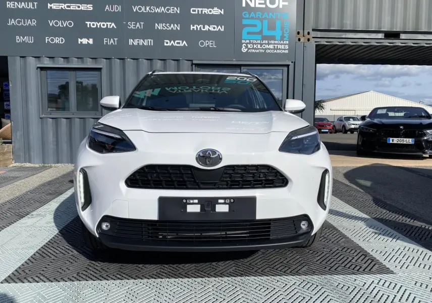 Vue frontale d'une Toyota Yaris Cross blanche pure avec calandre noire et phares LED distinctifs.