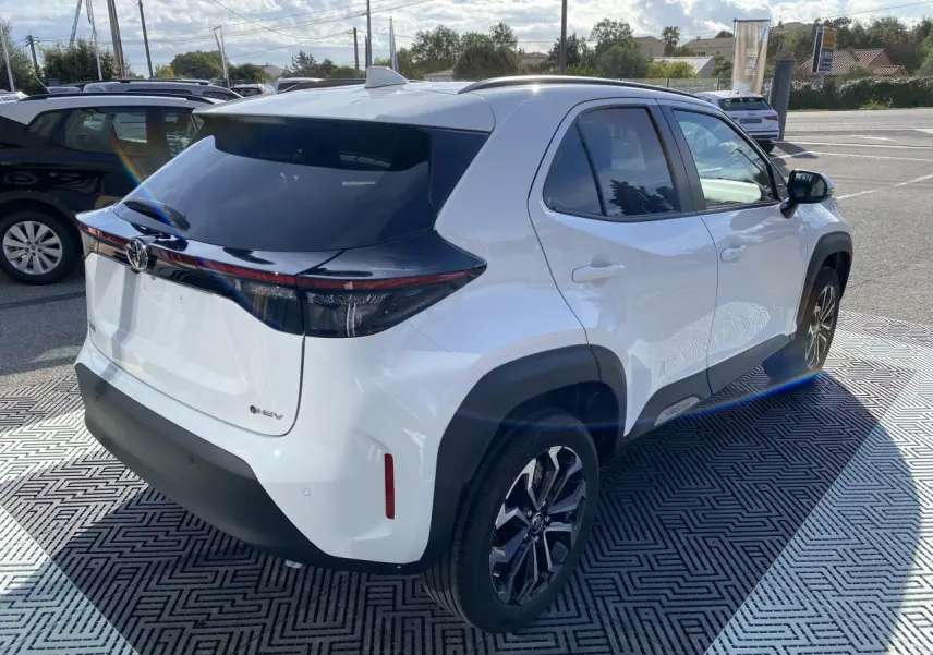Toyota Yaris Cross blanc pur en 3/4 arrière droit, avec toit noir, jantes alliage 17'' et feux arrière LED séquentiels.