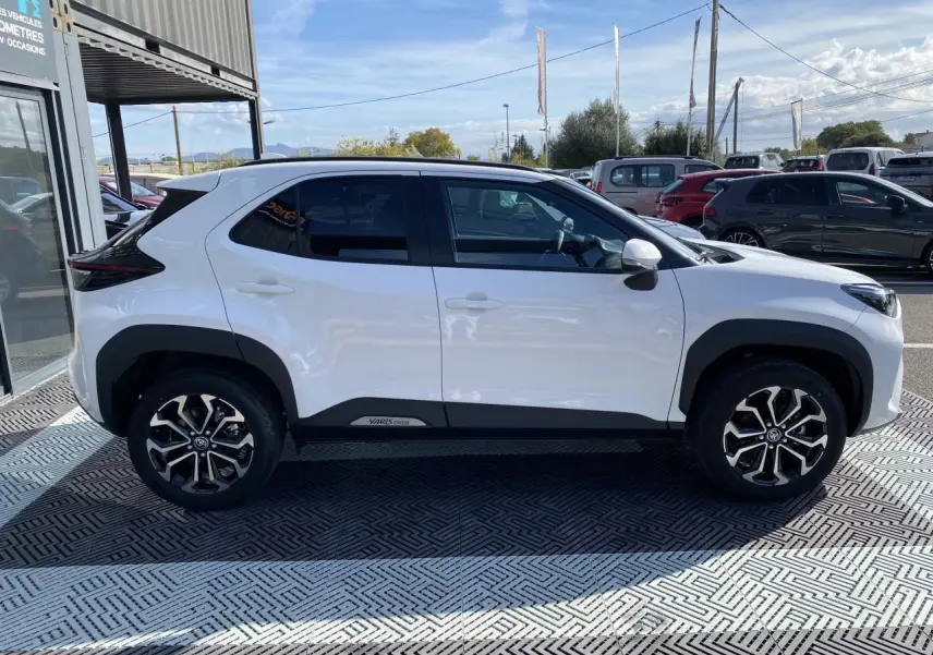 Profil côté gauche de la Toyota Yaris Cross blanche avec jantes alliage 17 pouces et vitres surteintées.