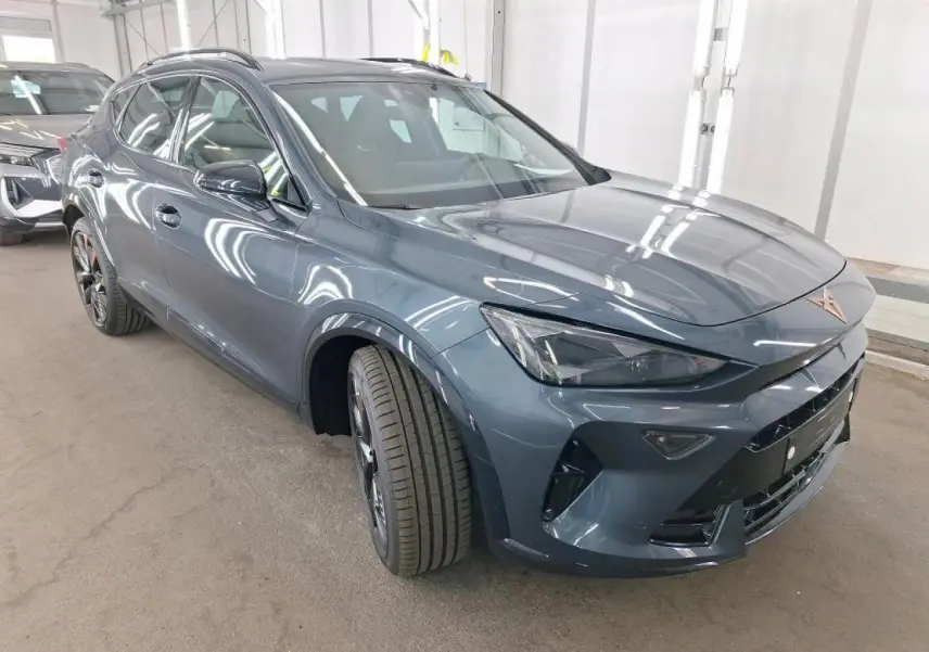 Vue 3/4 avant gauche d'une CUPRA Formentor 2024 gris magnétique avec jantes alliage noires et logo cuivré sur calandre