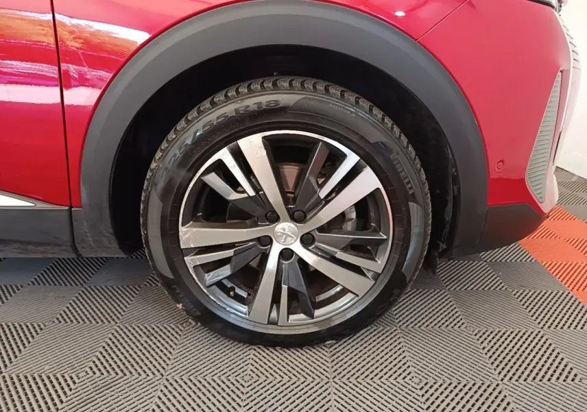 Gros plan sur la roue avant gauche du Peugeot 3008 rouge, avec jante alliage bicolore et pneu Pirelli.