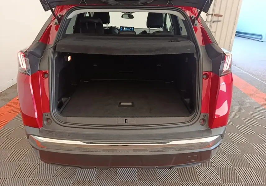 Vue arrière ouverte du coffre d’un Peugeot 3008 rouge, montrant un espace de chargement spacieux et la tablette cache-bagages.