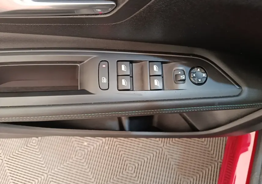 Gros plan sur la commande des vitres électriques et rétroviseurs sur la porte côté conducteur d’un Peugeot 3008 rouge.