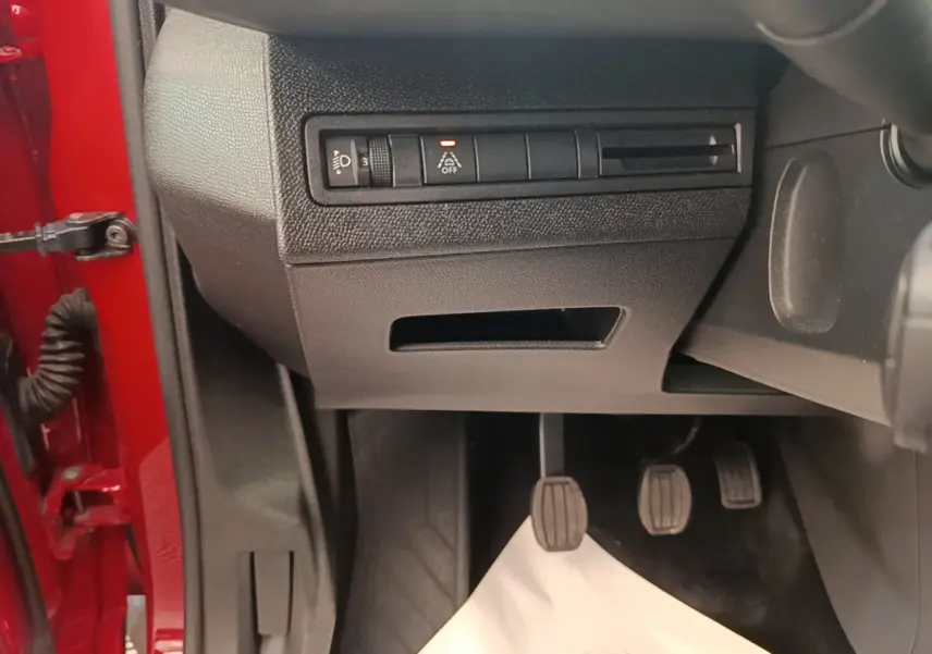Vue intérieure côté conducteur du Peugeot 3008 rouge, montrant les pédales et les commandes sous le tableau de bord.