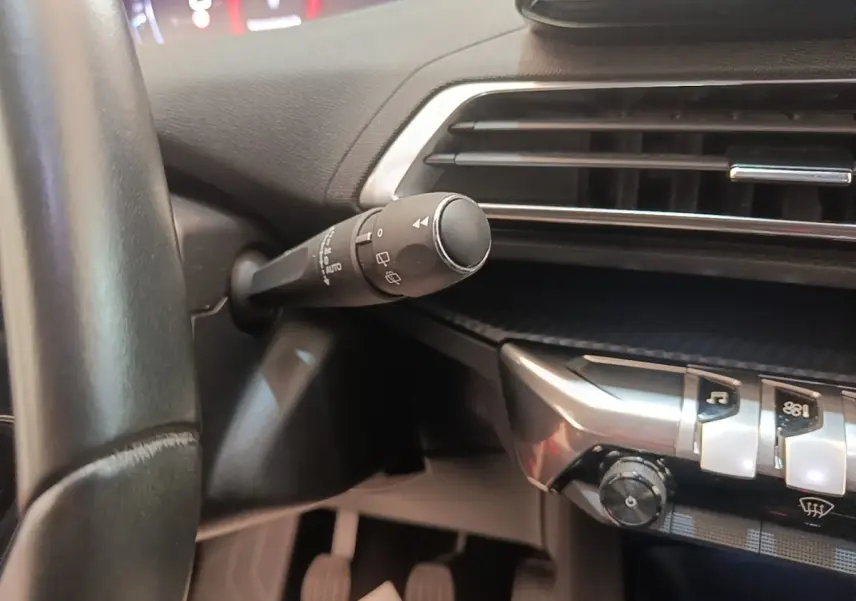 Gros plan intérieur sur la commande d’essuie-glace et la console centrale noire du Peugeot 3008 PureTech 130 S&S Allure 2021.
