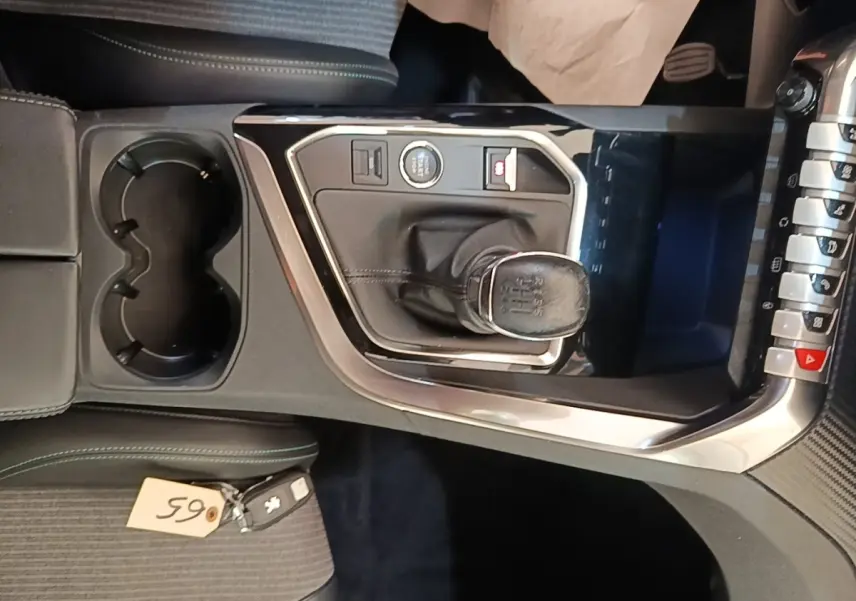 Vue rapprochée de la console centrale noire du Peugeot 3008 PureTech 130 avec levier de vitesse manuel et porte-gobelets.