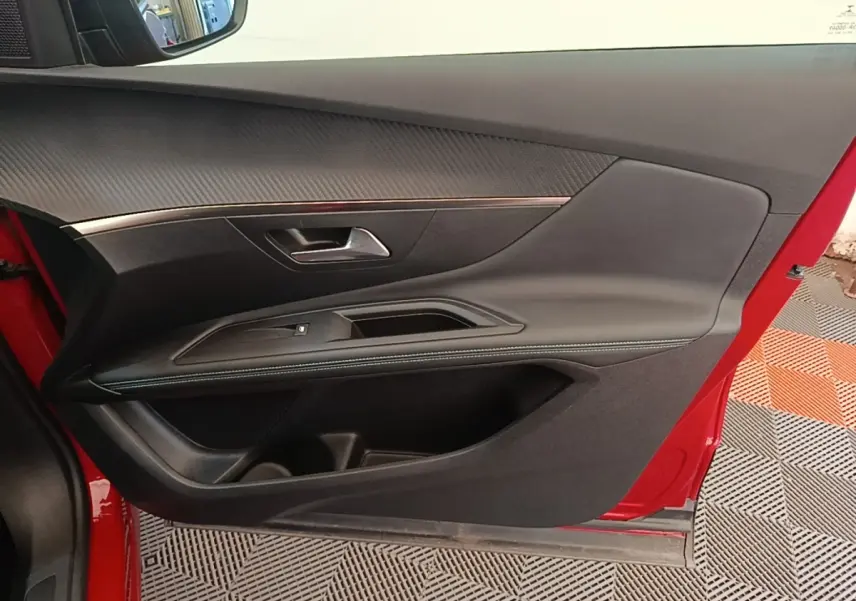 Vue latérale du panneau de porte avant gauche rouge du Peugeot 3008 avec garniture noire et insert décoratif chrome.