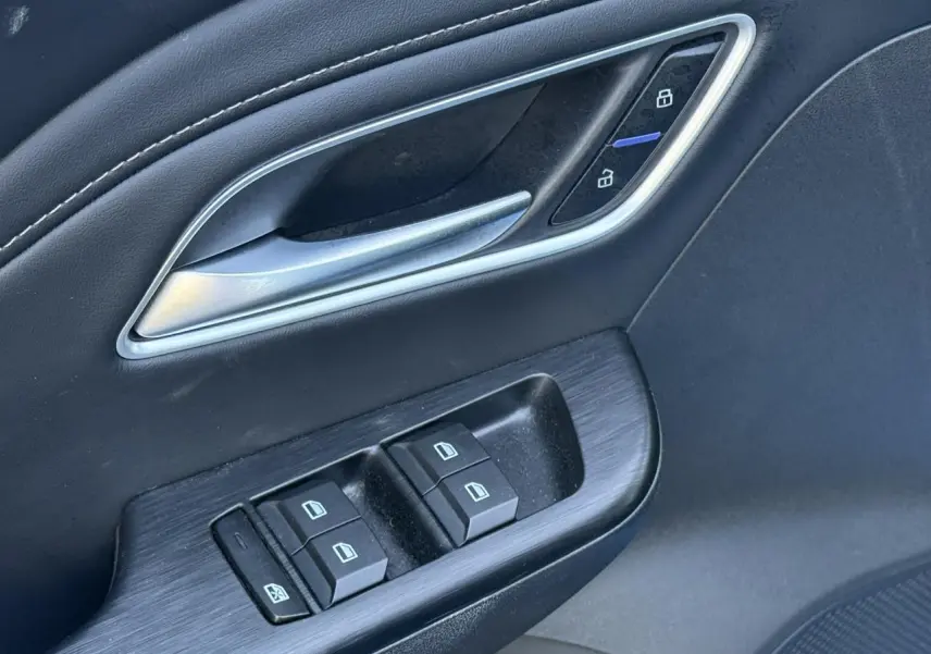 Gros plan sur la poignée de porte intérieure et les commandes des vitres côté conducteur du MG ZS 1.5 Hybrid+ 197 Luxury noir.