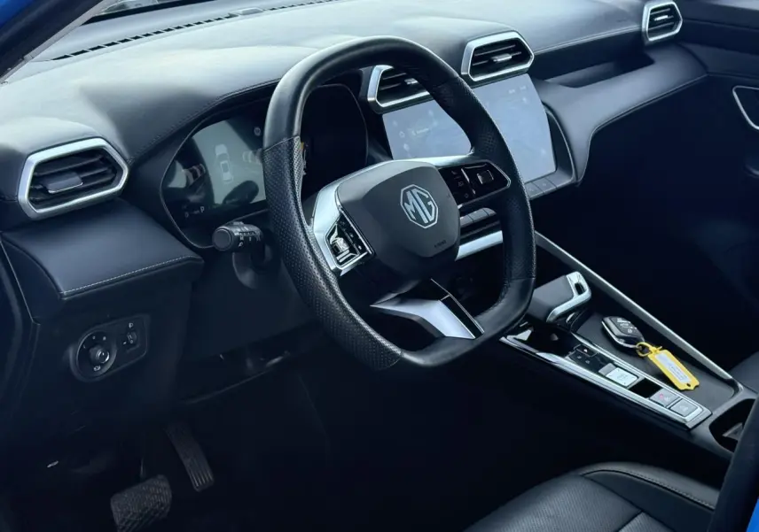 Vue intérieure côté conducteur du MG ZS 1.5 Hybrid+ 197 Luxury, volant cuir noir et écran tactile central.