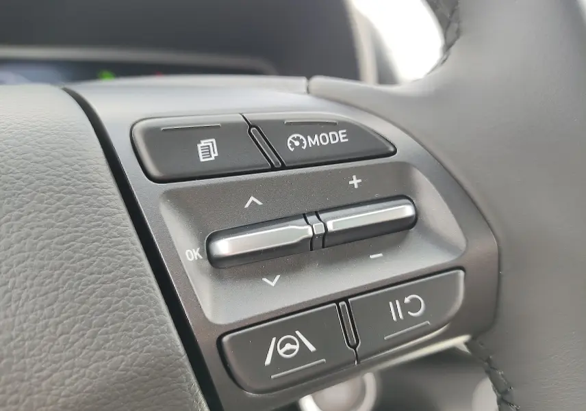 Gros plan sur les commandes multifonctions au volant cuir du Hyundai Kona Electric gris métallisé 2025.