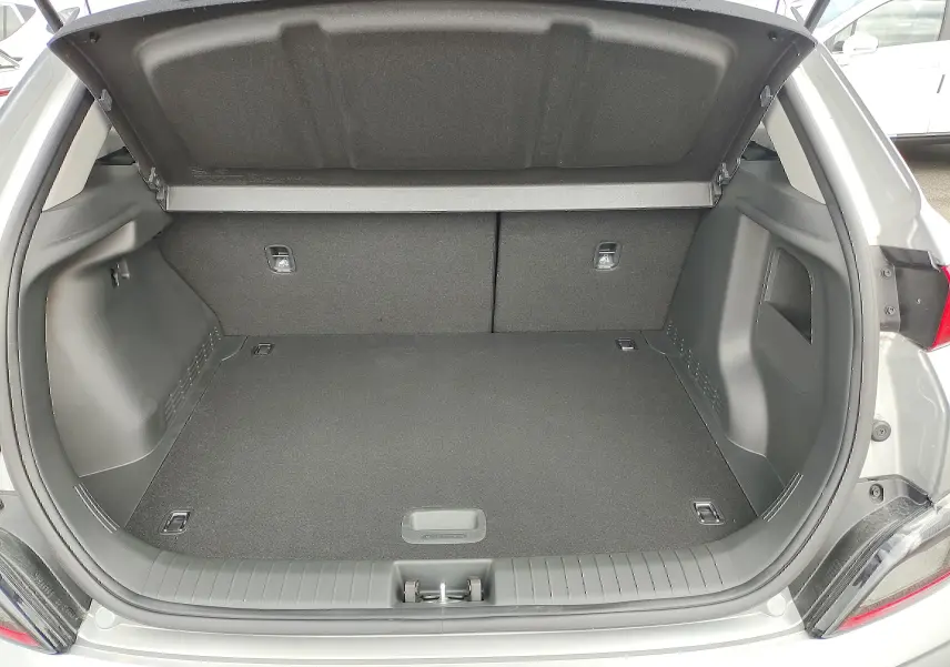 Coffre ouvert vu de l'arrière d'un Hyundai Kona Electric gris métallisé, espace de chargement vide et propre.