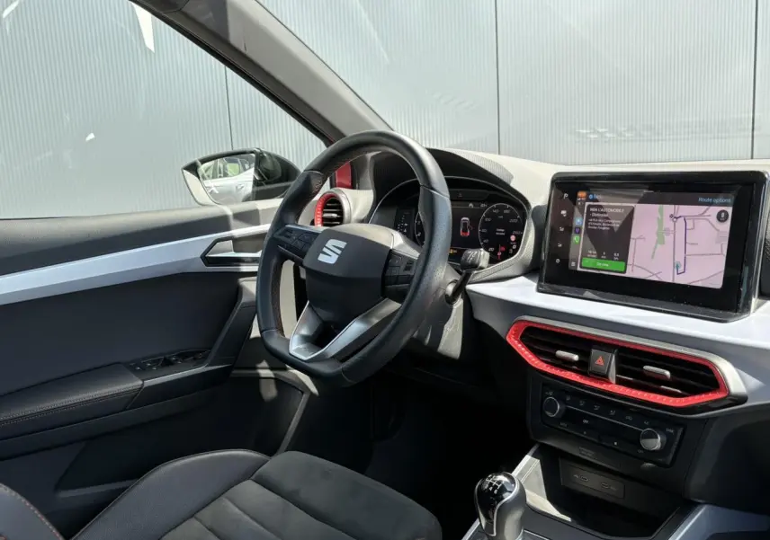 Intérieur côté conducteur du SEAT Arona TSI 110 FR 2024, avec volant multifonction, écran tactile et sellerie noire en suédine.