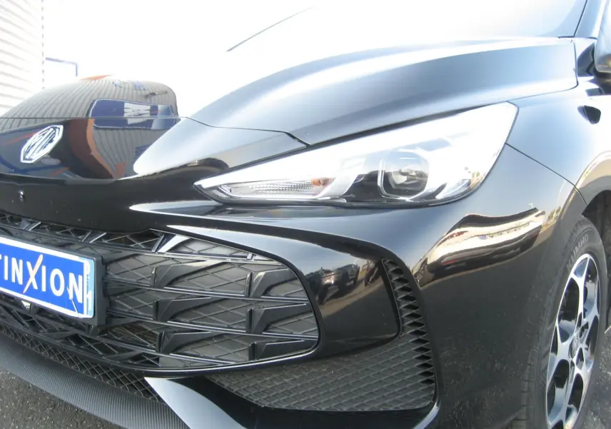 Gros plan sur l'avant droit noir brillant du MG3 1.5 HYBRID+ 195 CH LUXURY avec calandre et phare LED distinctifs.