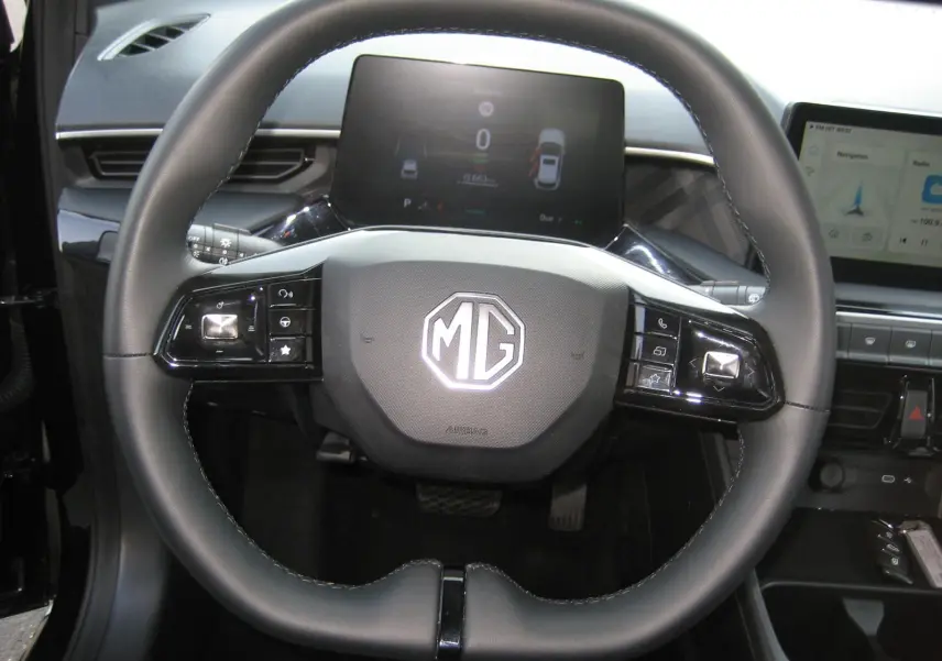 Vue rapprochée du volant noir du MG3 2024 avec commandes intégrées et tableau de bord numérique en arrière-plan.