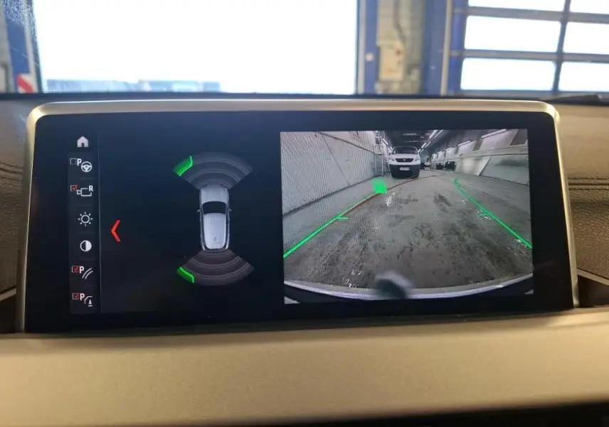 Écran intérieur de BMW X2 blanc montrant la caméra de recul et l’aide au stationnement active.