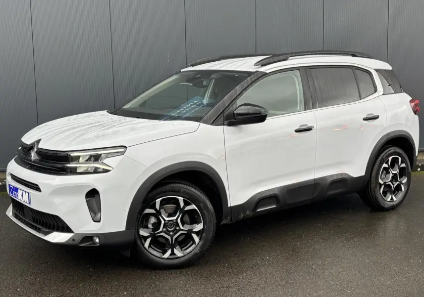 SUV Citroën C5 Aircross blanc Okénite en 3/4 avant droit avec jantes alliage bi-ton et barres de toit noires.