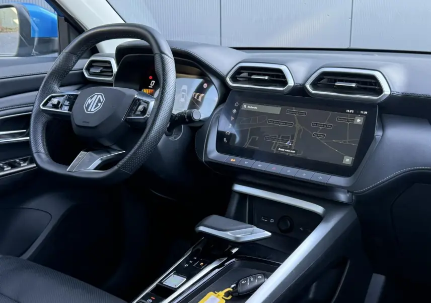 Vue intérieure côté conducteur du MG ZS 1.5 Hybrid+ 197 Luxury 2025, avec tableau de bord noir et écran tactile de navigation.