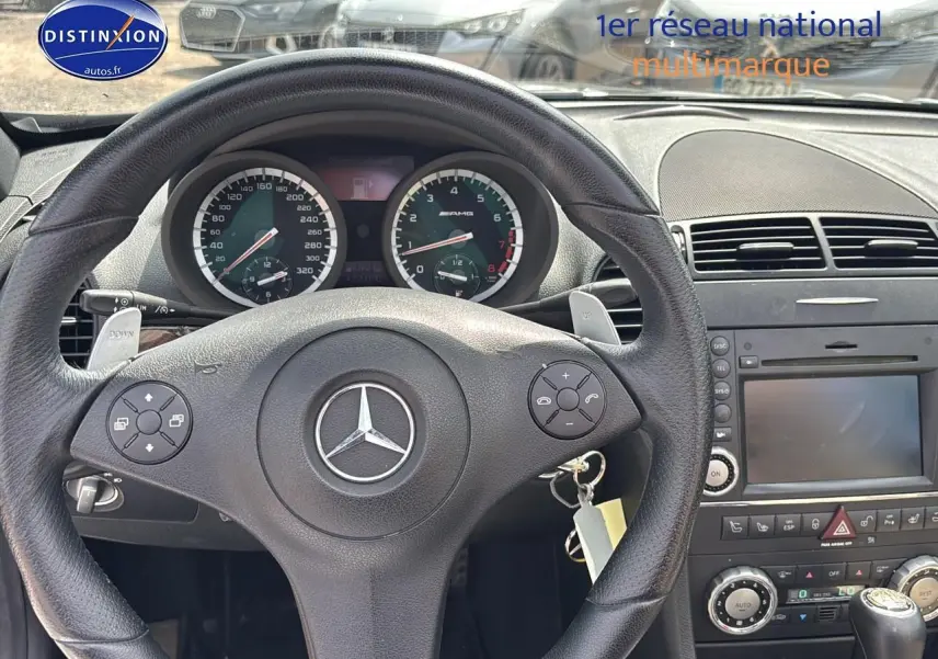 Vue intérieure centrée sur le volant cuir noir et le tableau de bord du Mercedes SLK 55 AMG 2009 avec commandes intégrées.