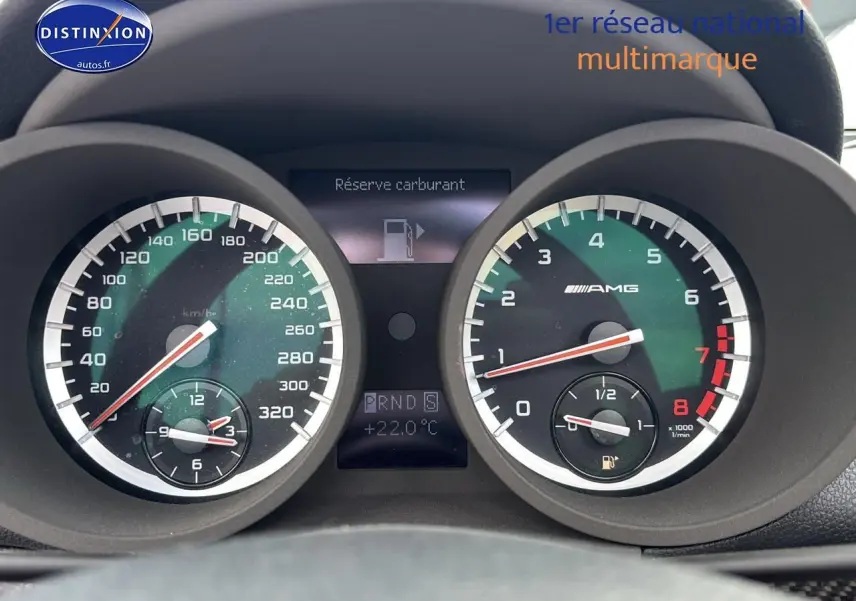 Gros plan sur le tableau de bord noir du Mercedes SLK 55 AMG 7G-Tronic, affichant le compteur et l'alerte réserve carburant.