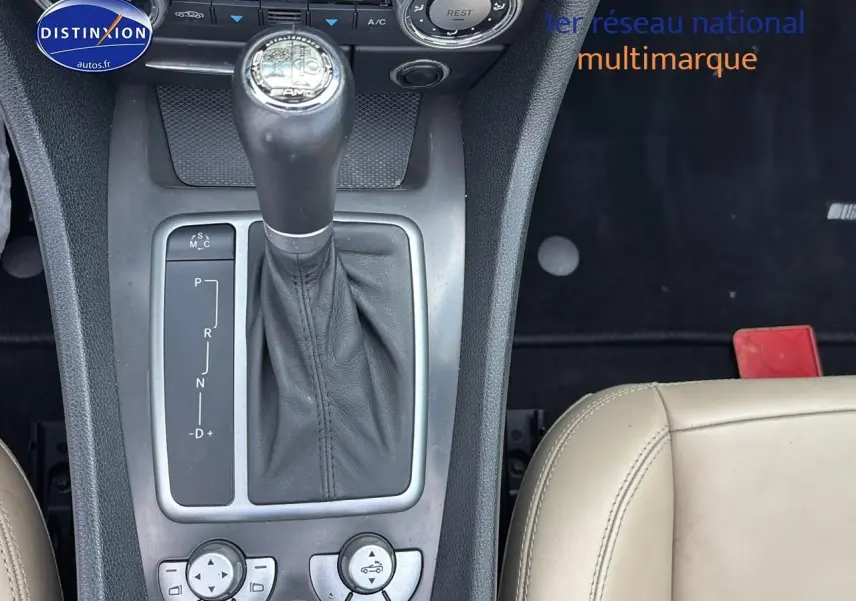 Gros plan sur la console centrale du Mercedes SLK 55 AMG noir de 2009 avec levier de vitesse automatique et sellerie cuir beige.