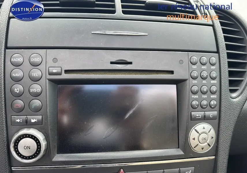 Tableau de bord noir de la Mercedes SLK 55 AMG 7G-Tronic 2009, avec écran central et commandes audio intégrées.