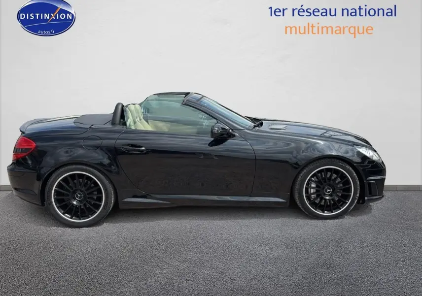 Profil côté gauche d'une Mercedes SLK 55 AMG noire cabriolet avec jantes noires et intérieur clair visible.