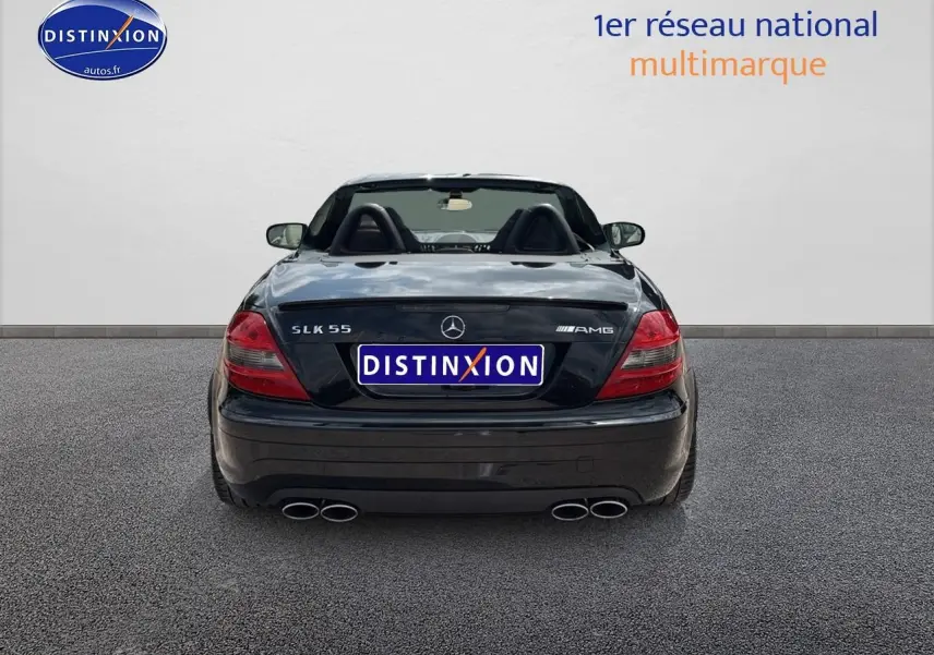 Vue arrière d'une Mercedes SLK 55 AMG noire de 2009, avec double sortie d'échappement et capote ouverte.