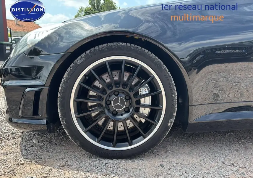 Gros plan sur la roue avant gauche noire d'une Mercedes SLK 55 AMG 7G-Tronic avec jante alu noire et logo Mercedes central.