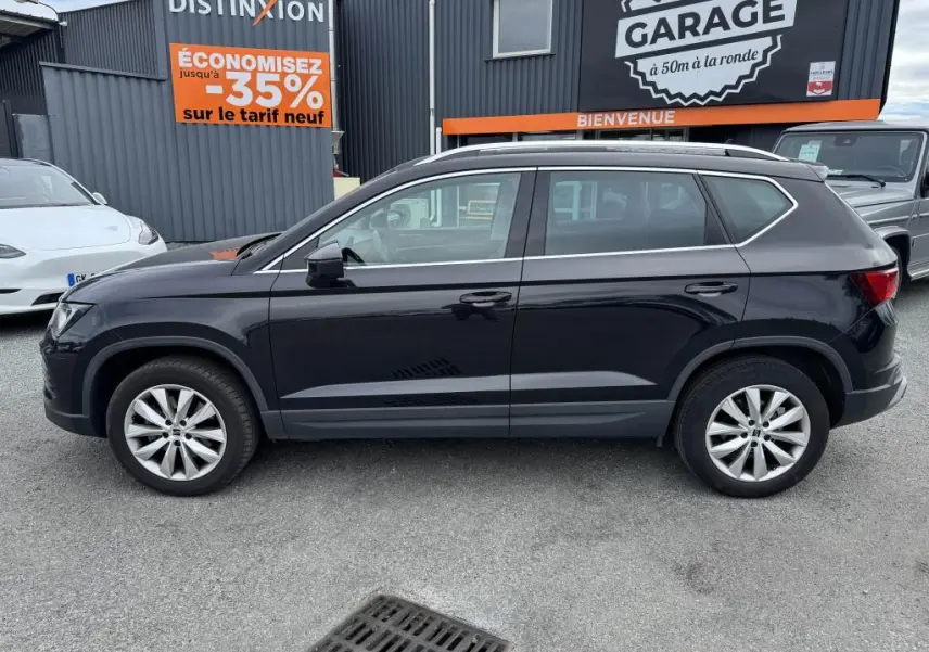 Profil côté gauche d'un SUV SEAT Ateca noir métallisé avec jantes alliage 17'' et barres de toit chromées.