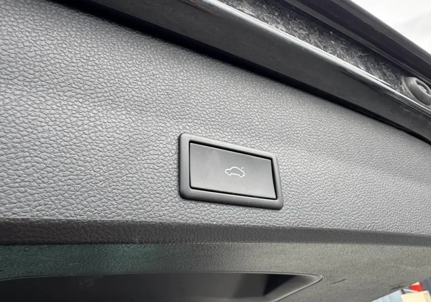 Bouton d'ouverture électrique du coffre sur la garniture intérieure noire du hayon d'un SEAT Ateca noir 2023.