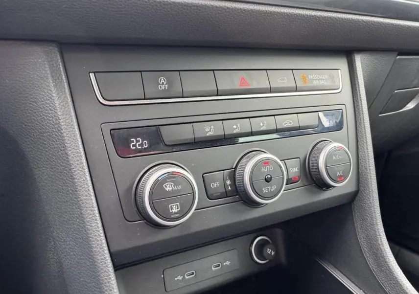 Vue rapprochée de la console centrale noire du SEAT Ateca 2023, avec commandes climatisation et prises USB-C éclairées.