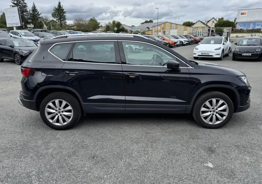 Vue latérale droite d'un SUV SEAT Ateca noir métallisé avec jantes alliage 17'' sur un parking extérieur.