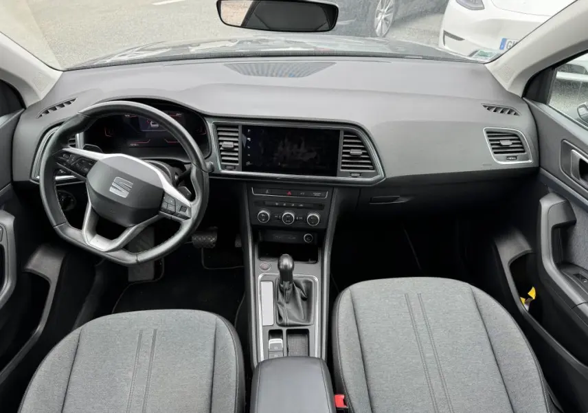 Vue intérieure avant du SEAT Ateca 2023 noir, montrant le tableau de bord, volant multifonction et sièges en textile gris.