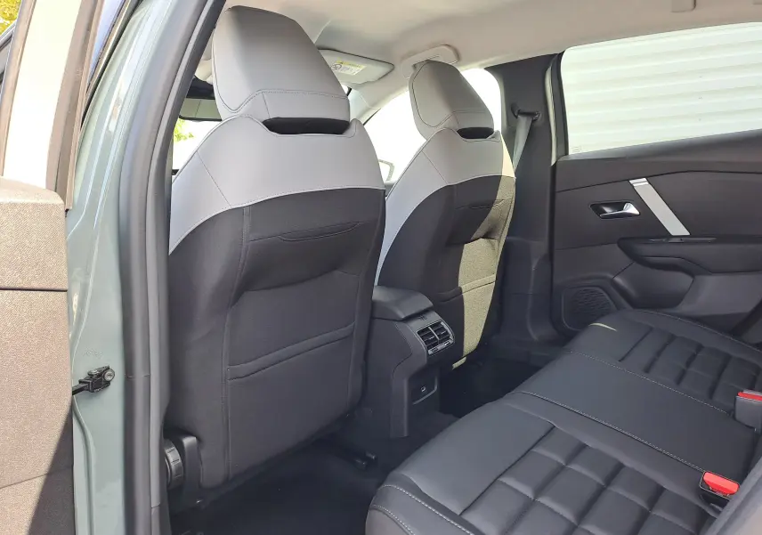 Vue arrière intérieure du Citroën C4 hybride 2025 Manhattan Green, sièges bicolores noirs et gris avec console centrale.
