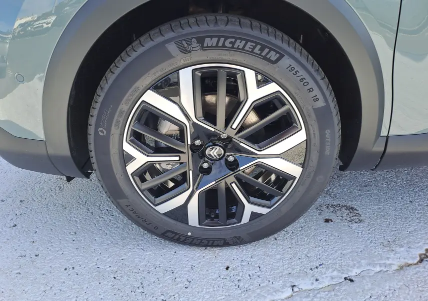 Gros plan sur la roue avant gauche de la Citroën C4 hybride 2025 Manhattan Green avec jante alliage noire et argent.