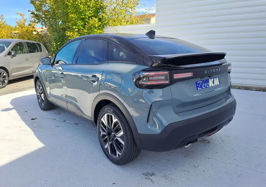 Vue 3/4 arrière droite d'une Citroën C4 hybride 2025 Manhattan Green avec toit noir et feux arrière LED distinctifs.