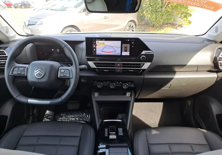 Intérieur de la Citroën C4 hybride 2025 vu de face, tableau de bord moderne avec écran tactile et volant multifonction.