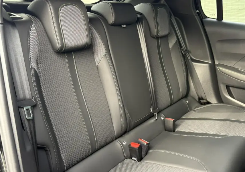 Vue rapprochée de la banquette arrière noire avec surpiqûres blanches et ceintures de sécurité dans une Peugeot 208 2023.
