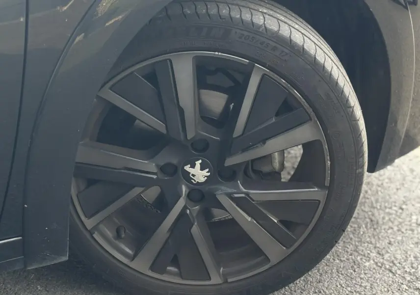 Gros plan sur la roue avant gauche noire avec jante alliage 17'' du Peugeot 208 GT noir perla.