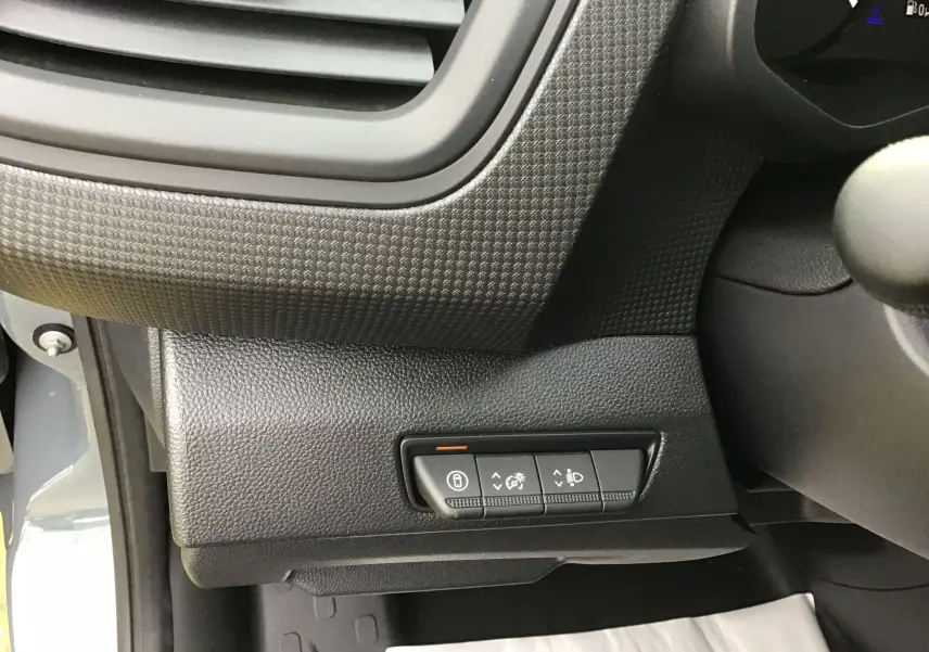 Détail intérieur du tableau de bord côté gauche du Renault Trafic Fourgon gris urbain, avec commandes d’éclairage et verrouillage.