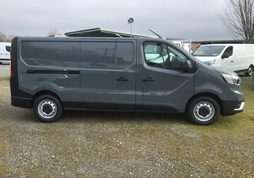 Vue de profil côté gauche du Renault Trafic Fourgon gris urbain 2025, avec porte latérale coulissante fermée.