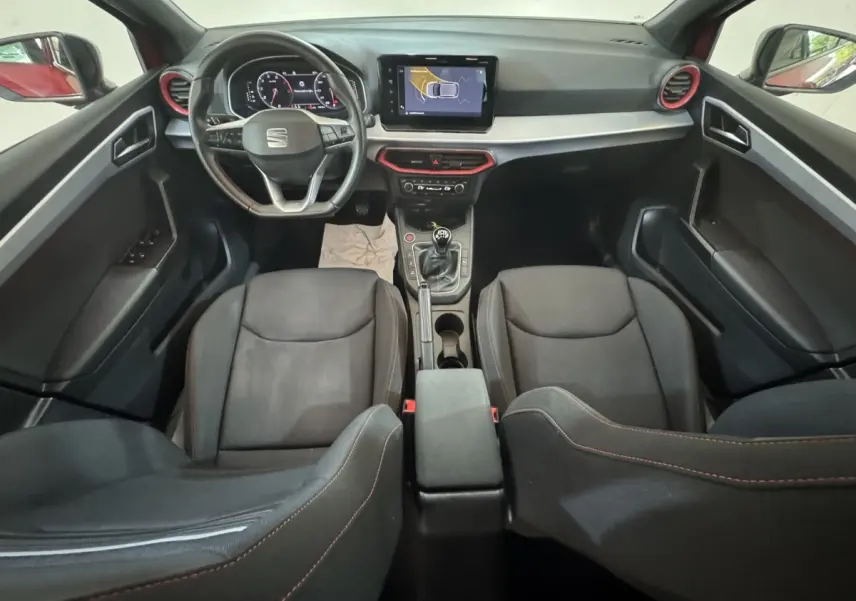 Vue intérieure avant du tableau de bord et des sièges noirs de la SEAT IBIZA 1.0 TSI 110 FR avec volant cuir et écran tactile central.