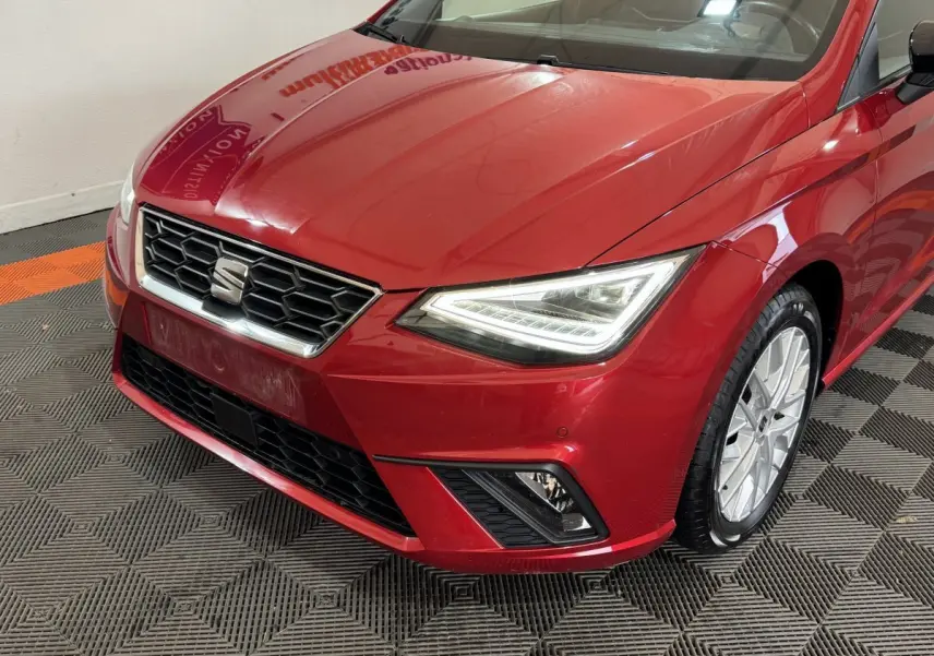 Vue 3/4 avant droit d'une SEAT IBIZA rouge 2024 avec phares LED et jantes alliage visibles.