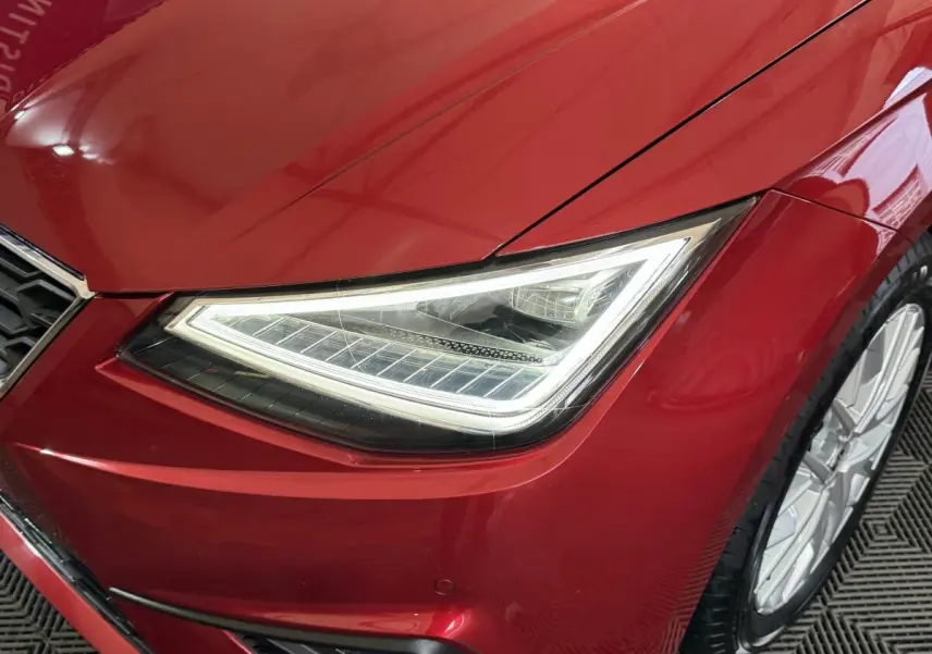 Gros plan sur le phare avant droit LED d'une SEAT IBIZA 1.0 TSI 110 FR rouge 2024, avec jante alu visible.