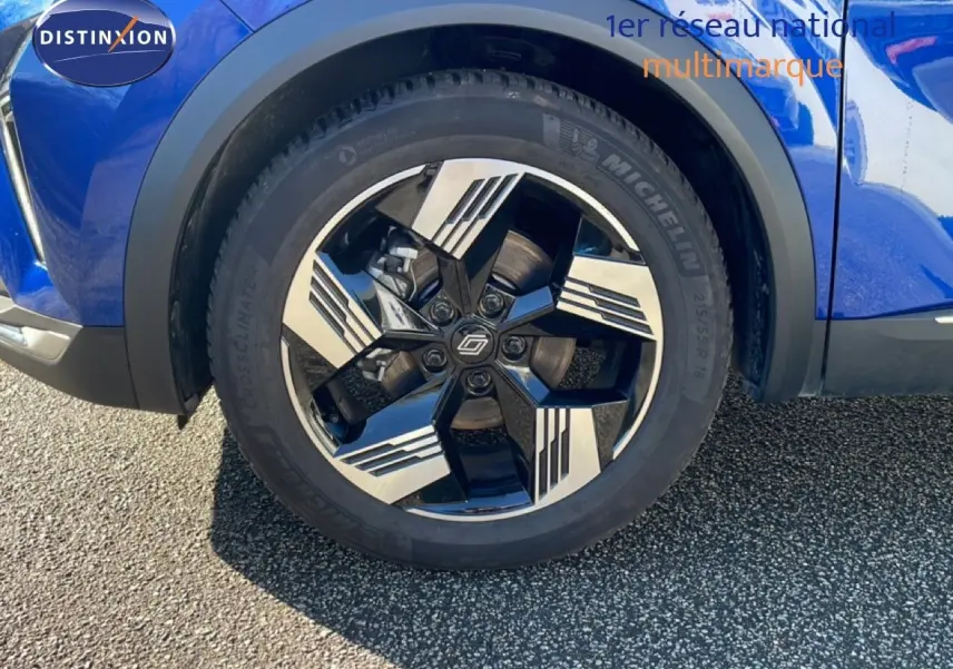 Gros plan sur la roue avant droite du Renault Symbioz bleu iron metal avec jante noire et argentée au design géométrique.