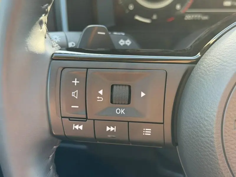 Gros plan sur les commandes multifonctions noires au volant cuir du Nissan Qashqai 2025, côté gauche.