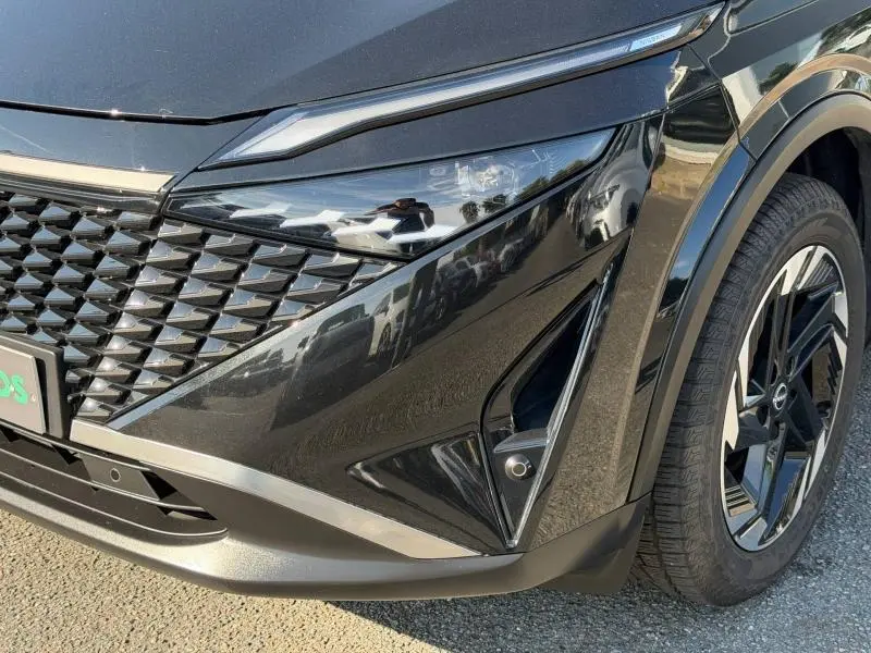 Gros plan sur l'avant droit noir Kuro métallisé du Nissan Qashqai 2025, avec phares LED et jante alu noire.
