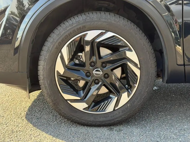 Gros plan sur la roue avant gauche du Nissan Qashqai noir Kuro Métallisé avec jante alu au design moderne.