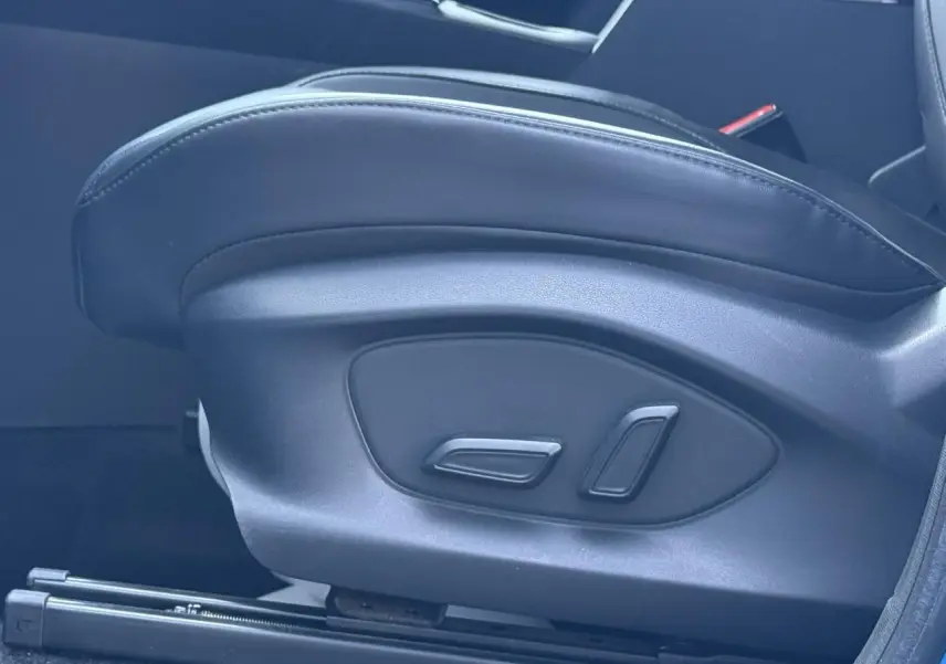 Gros plan sur les commandes électriques du siège conducteur noir du MG MOTOR ZS 1.5 Hybrid+ 197 Luxury 2025.
