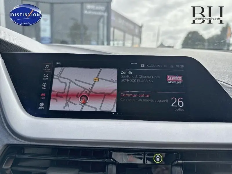 Écran tactile central de la BMW Série 1 116dA 2022 affichant navigation et radio Skyrock, vue intérieure avant.